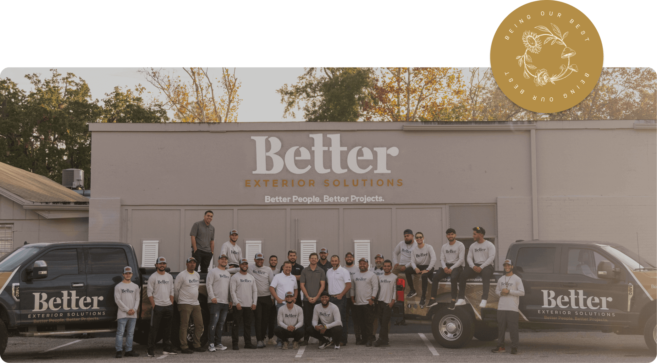 The Better Exteriors Team outside their warehouse all the staff and both their branded trucks