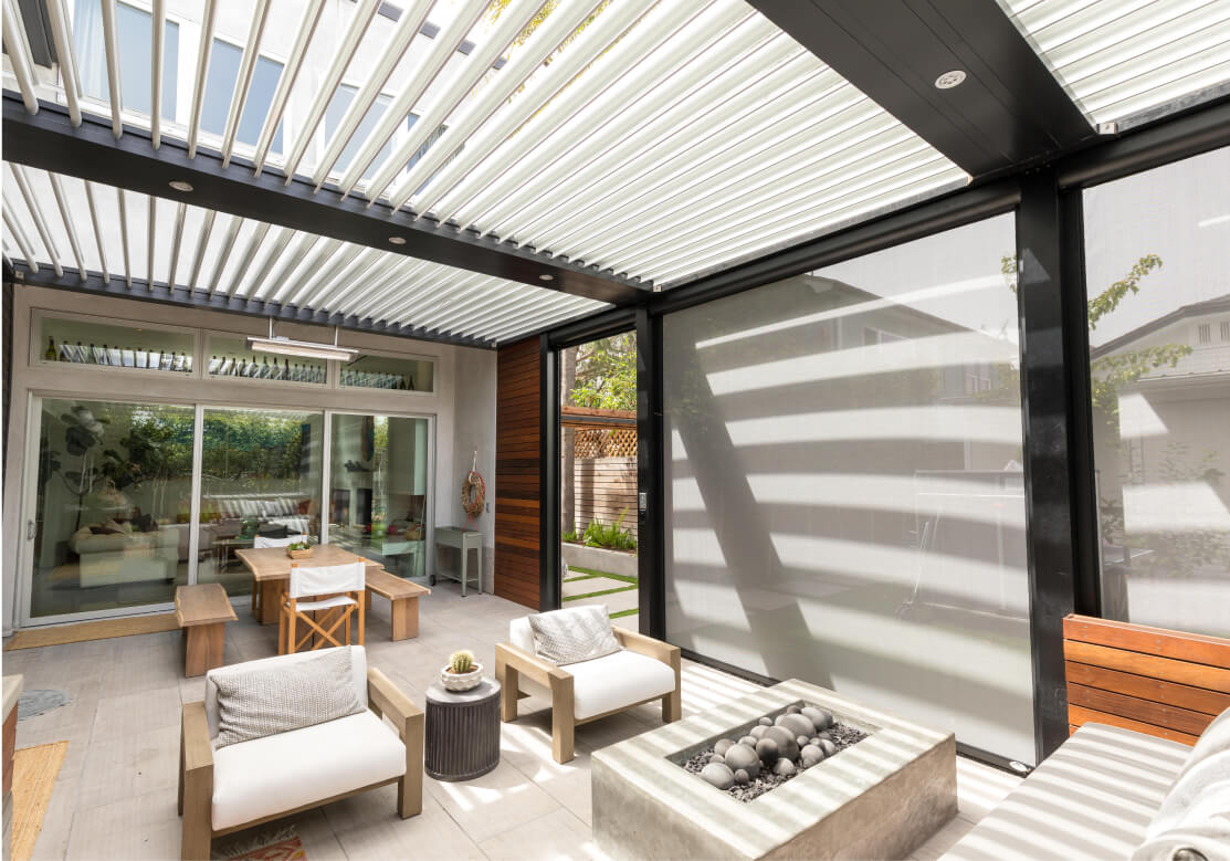 a patio covered by a motorized pergola with white retractable screens connected to it installed by Better Exteriors